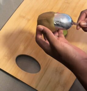Spoon sliding between kiwi skin and fruit