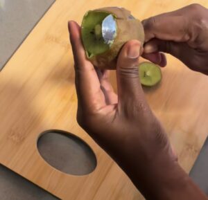 Spoon sliding between kiwi skin and fruit